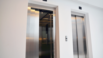 A modern stainless steel elevator in a white room.